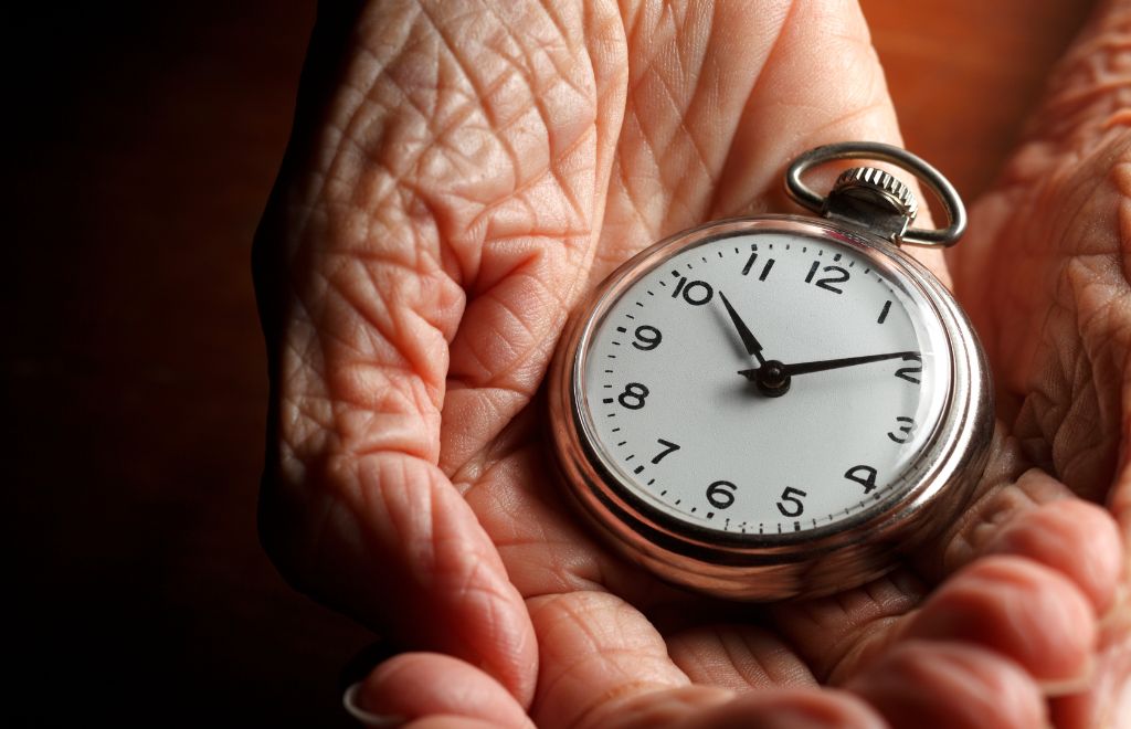 altern Eine menschliche Hand hält eine Taschenuhr.
